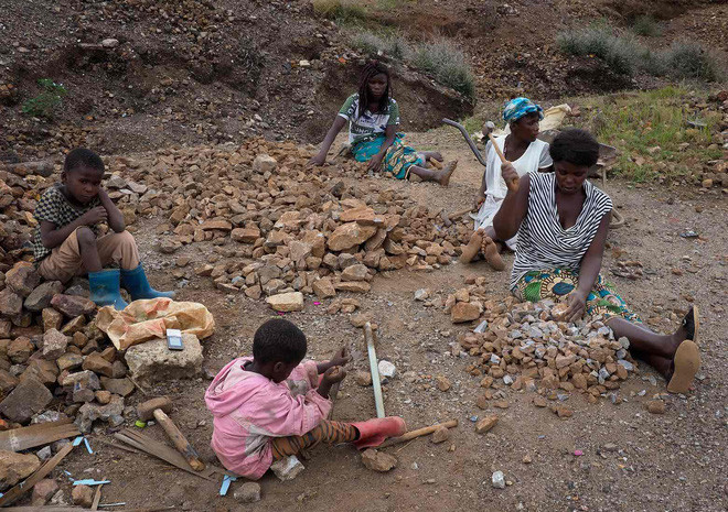 Phụ nữ và trẻ em chặt nhỏ đá để bán tại khu vực bị phơi nhiễm chì gần khu vực khai mỏ trước đây.