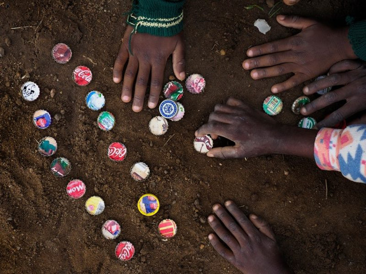 Trẻ em chơi nắp trai nước giải khát trên nền đất nhiễm chì tại thị trấn Kabwe.