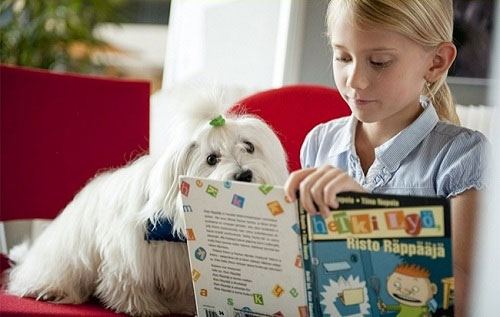 Chú chó lắng nghe trẻ đọc sách.