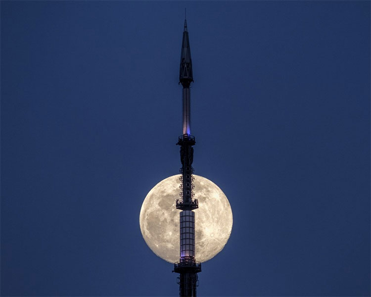 Trăng tròn xuất hiện phía sau tháp anten trên đỉnh Tòa nhà Thương mại One World ở New York, Mỹ. 
