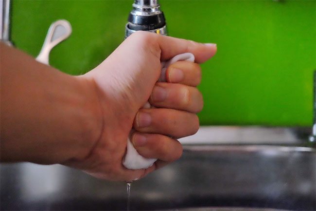 Bóp nhẹ khẩu trang trong lòng bàn tay để vắt bớt nước