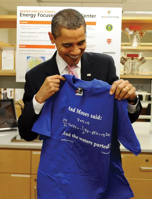 Cựu Tổng thống Mỹ Barrack Obama cầm trên tay chiếc áo ghi dòng chữ nhắc tới cả phương trình Navier-Stokes